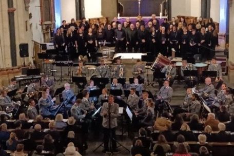 Man sieht den KuBa-Chor im Altarraum der Kirche in Münstermaifeld, davor das Heeresmusikkorps Koblenz mit Instrumenten und in Gala-Uniform