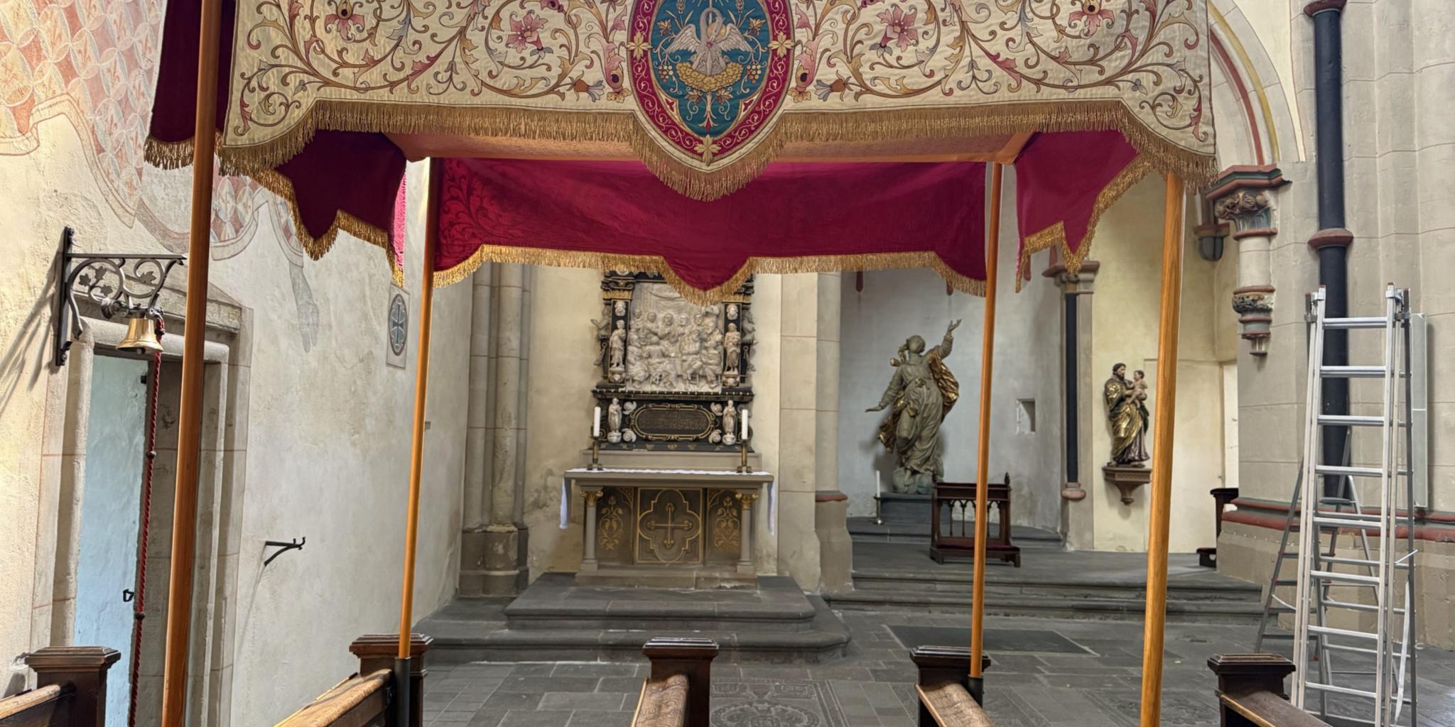 Man sieht den reich mit Goldstickereien verzierten 'Himmel'/Baldachin an vier Stangen aufgehängt