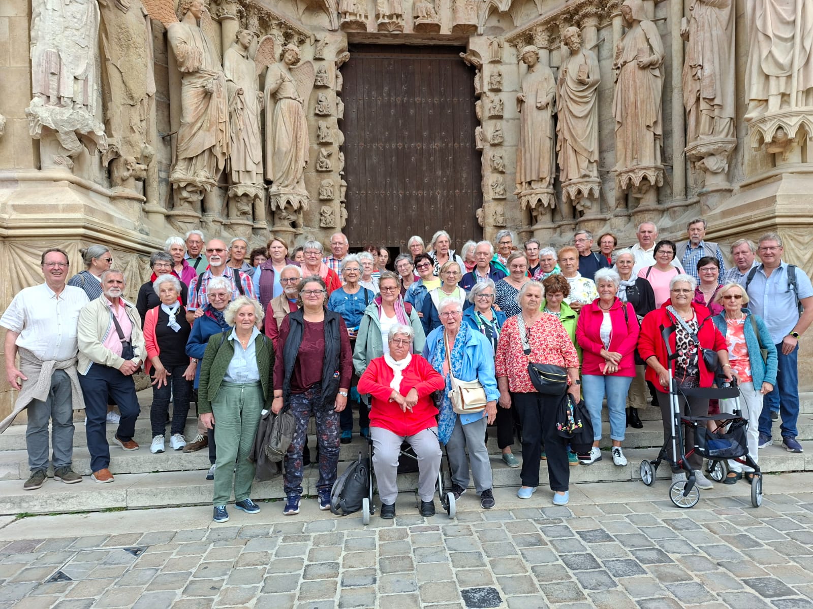 Man sieht eine große Gruppe Senioren vor dem eindrucksvoll verzierten Portal der Kathedrale in Metz stehen