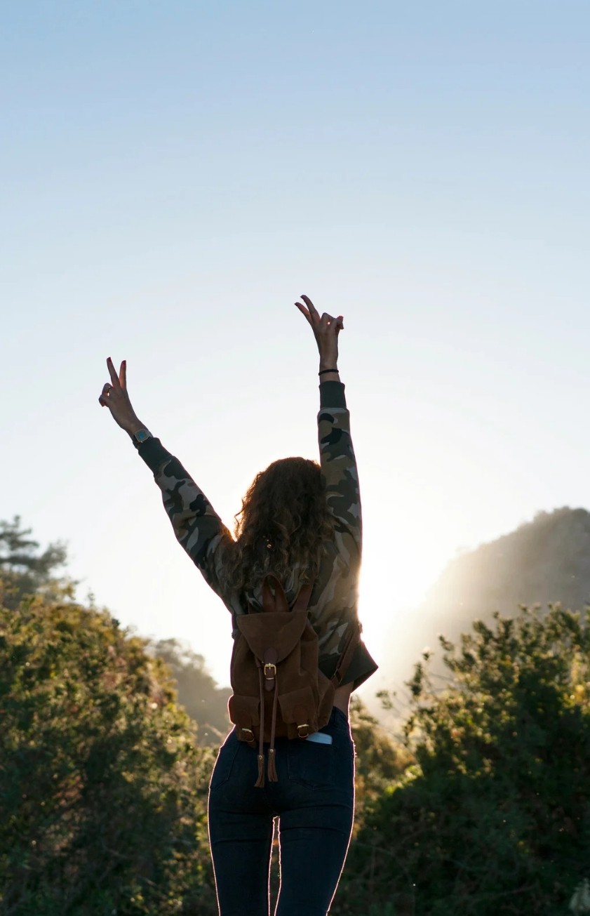 Man sieht eine Jugendliche von hinten, die vor Freude hochspringt und die Arme hochreißt