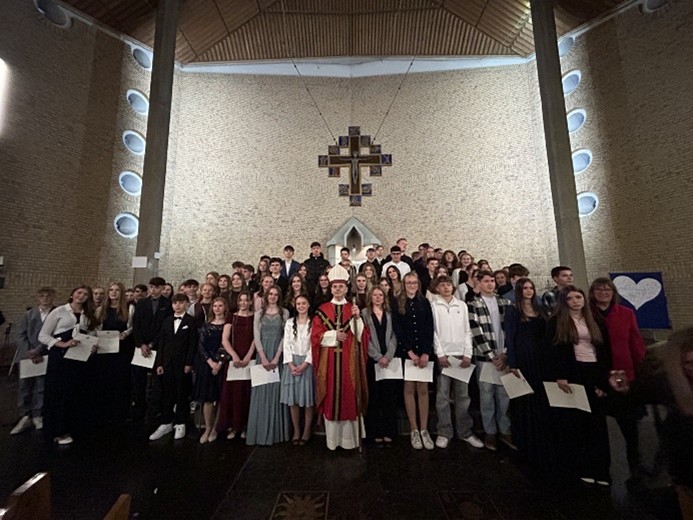 Man sieht die Firmbewerber des Pastoralen Raums Maifeld im Altarraum der Ochtendunger Kirche mit Weihbischof Robert Brahm