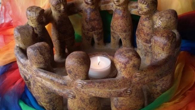 Man sieht auf einem bunten Tuch als Untergrund einen Specksteinkreis (Kerzenhalter) aus Figuren, die einander an den Schultern fassen - ein sogenannter 'Freundeskreis'