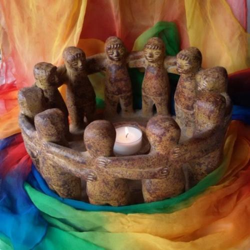 Man sieht auf einem bunten Tuch als Untergrund einen Specksteinkreis (Kerzenhalter) aus Figuren, die einander an den Schultern fassen - ein sogenannter 'Freundeskreis'
