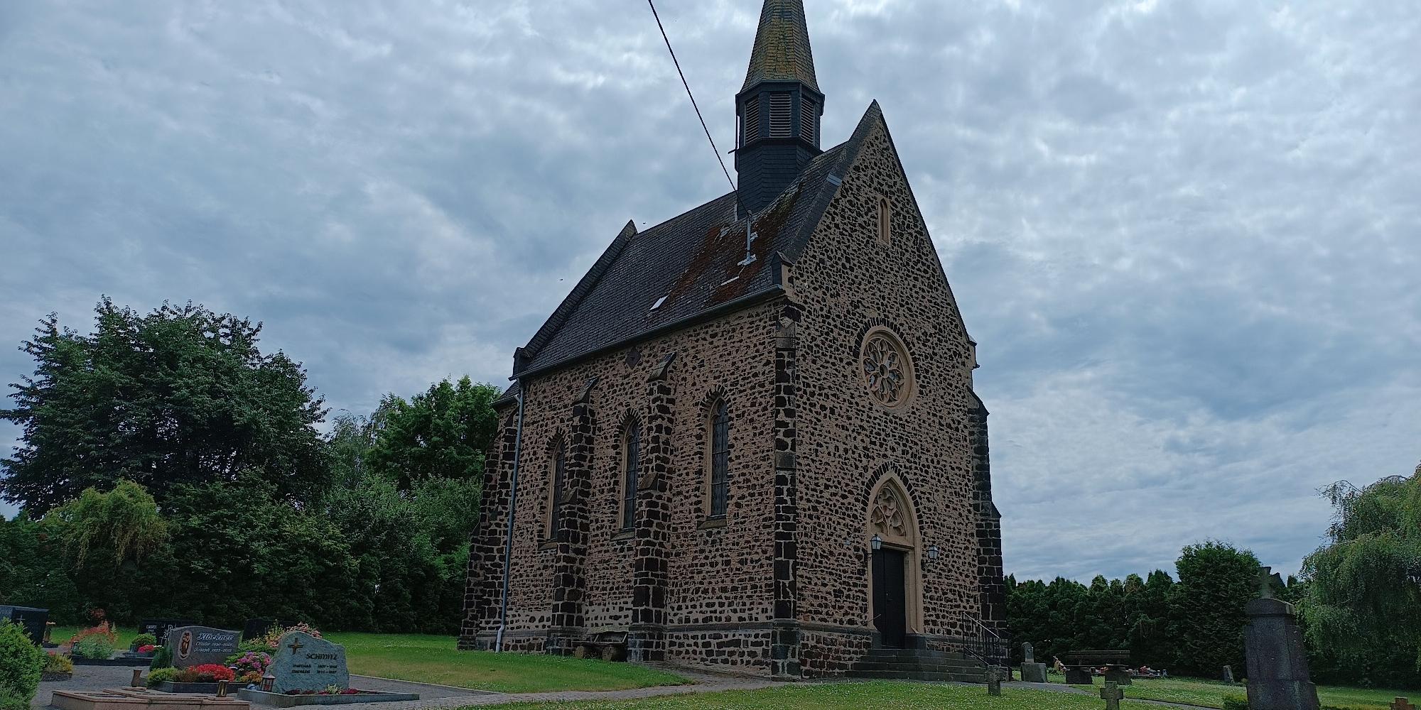 aus dunklem Sandstein gemauerte Kirche, Eingang vom Friedhof her