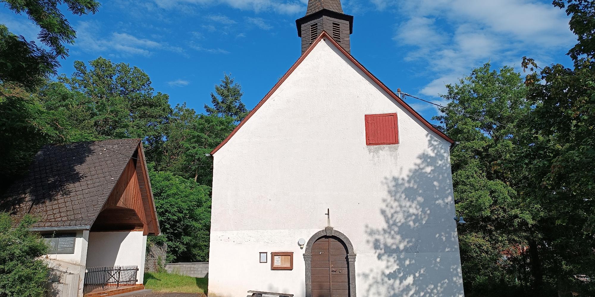 Blick auf den Kircheneingang mit kleiner Kapelle links