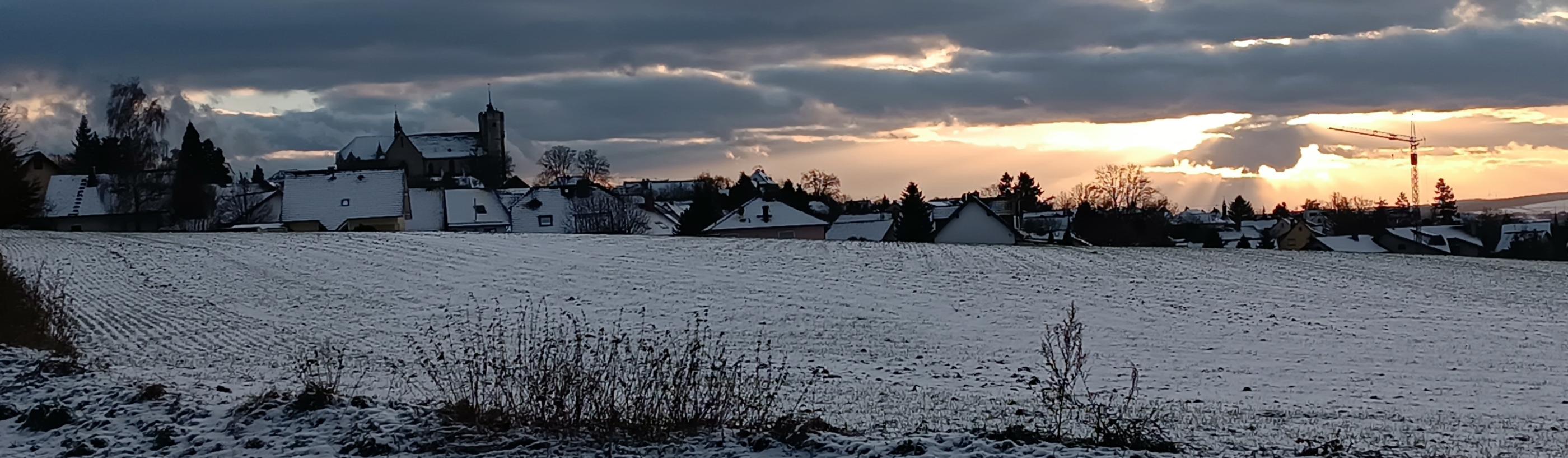 Man sieht die Silhouette der Stadt Muenstermaifeld im Abendlicht bei Schnee