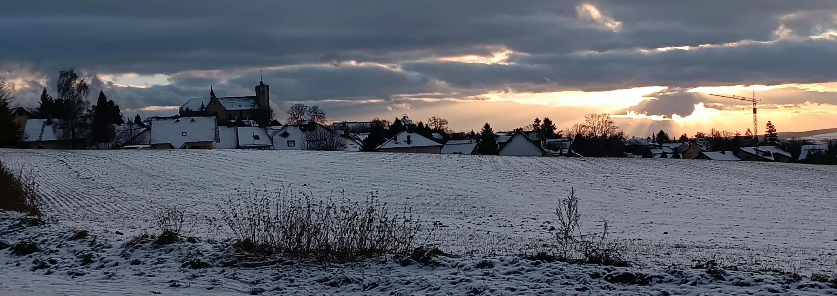 Man sieht die Silhouette der Stadt Muenstermaifeld im Abendlicht bei Schnee