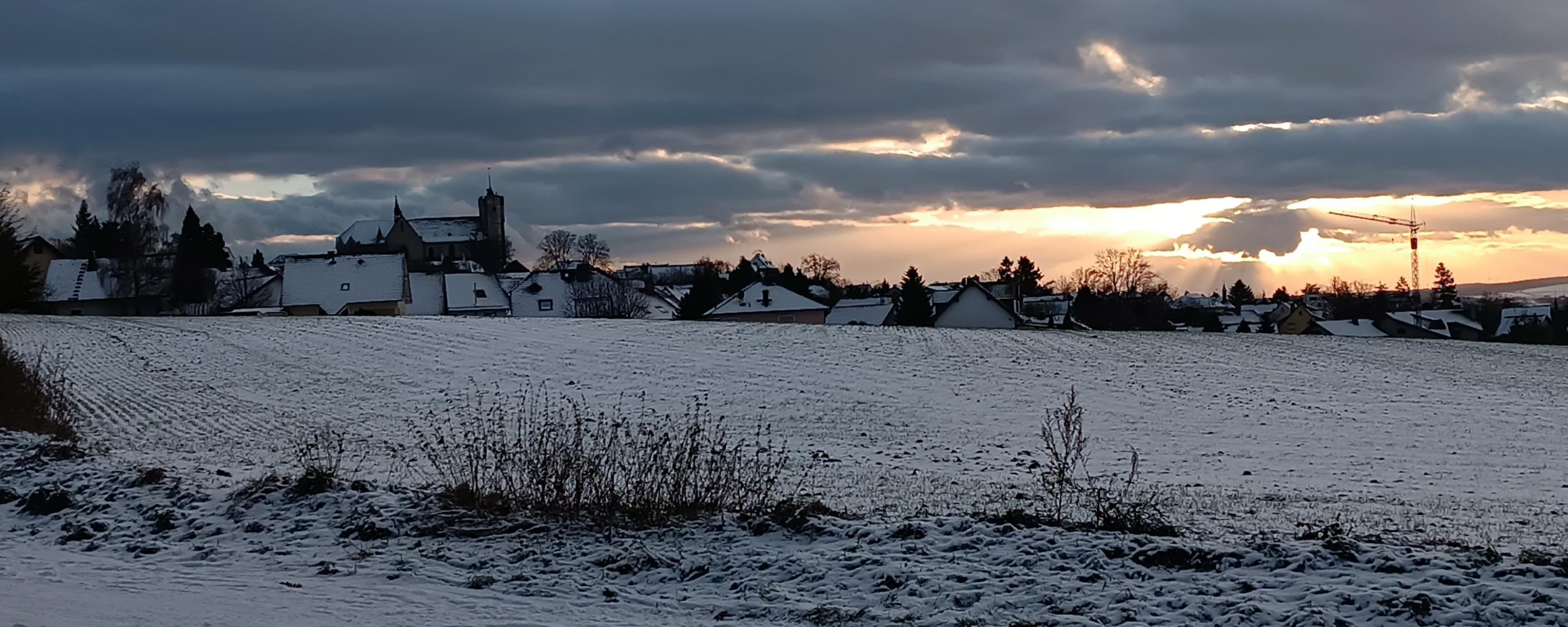 Man sieht die Silhouette der Stadt Muenstermaifeld im Abendlicht bei Schnee