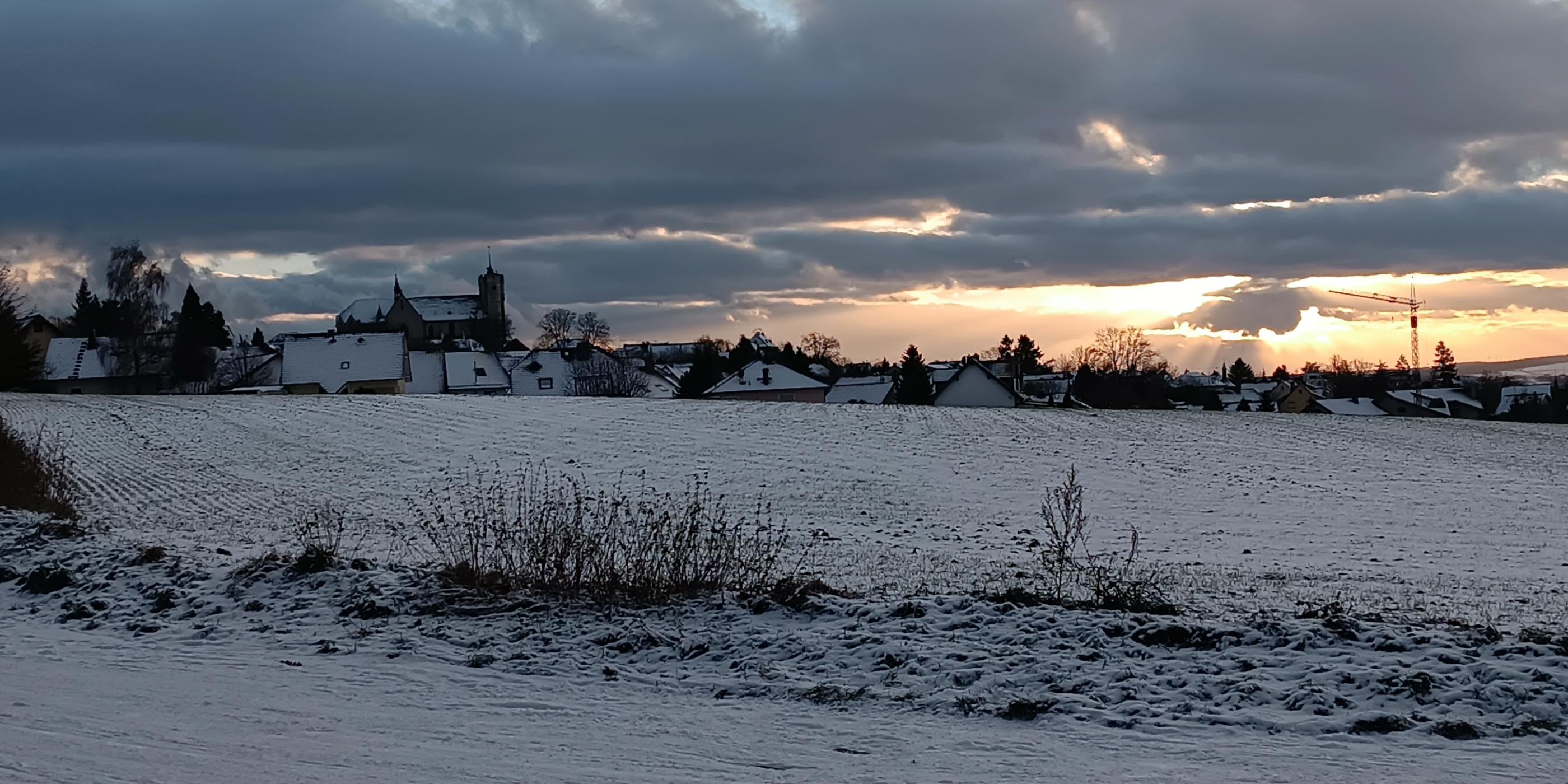 Man sieht die Silhouette der Stadt Muenstermaifeld im Abendlicht bei Schnee