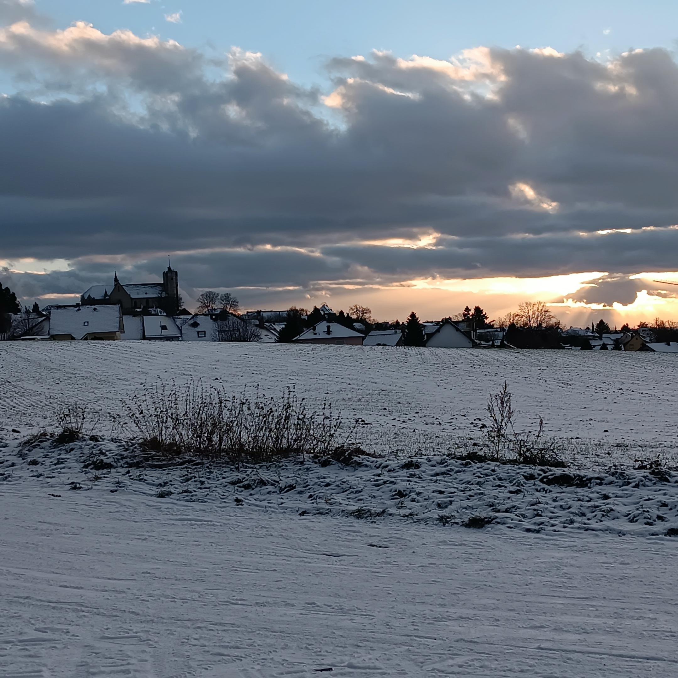 Man sieht die Silhouette der Stadt Muenstermaifeld im Abendlicht bei Schnee