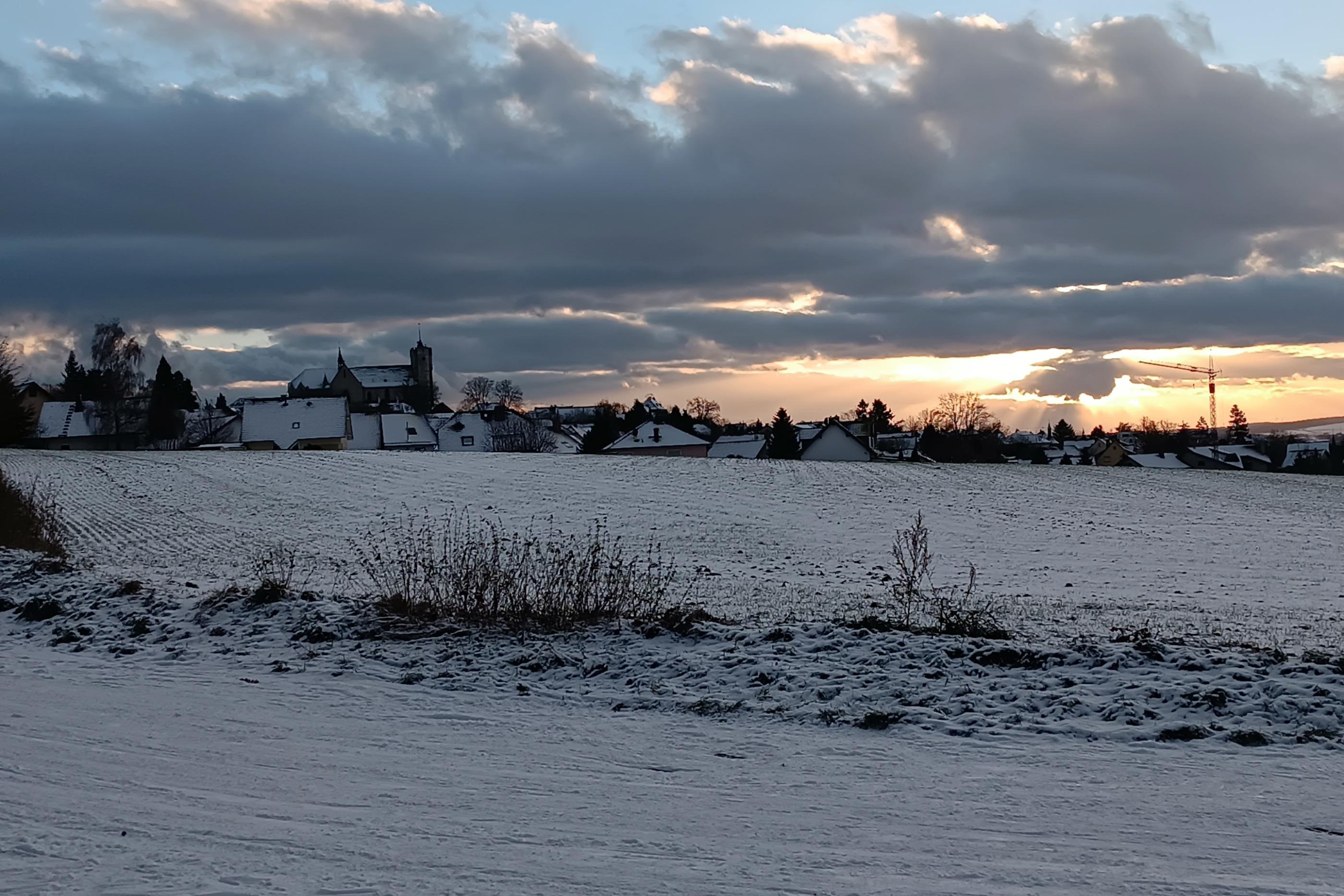 Man sieht die Silhouette der Stadt Muenstermaifeld im Abendlicht bei Schnee