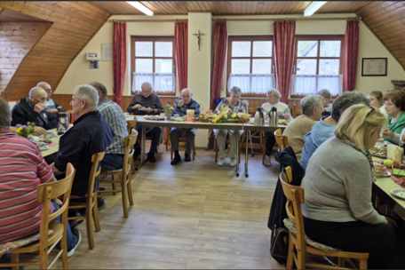 Man sieht einen Saal in dem Menschen Kaffee trinken und Kuchen essen