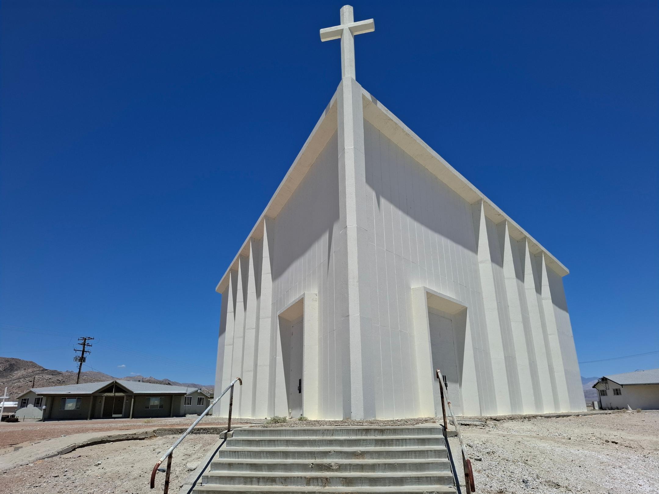 Man sieht eine weiß gestrichene, aus Holz gebaute Kirche in der Wüste