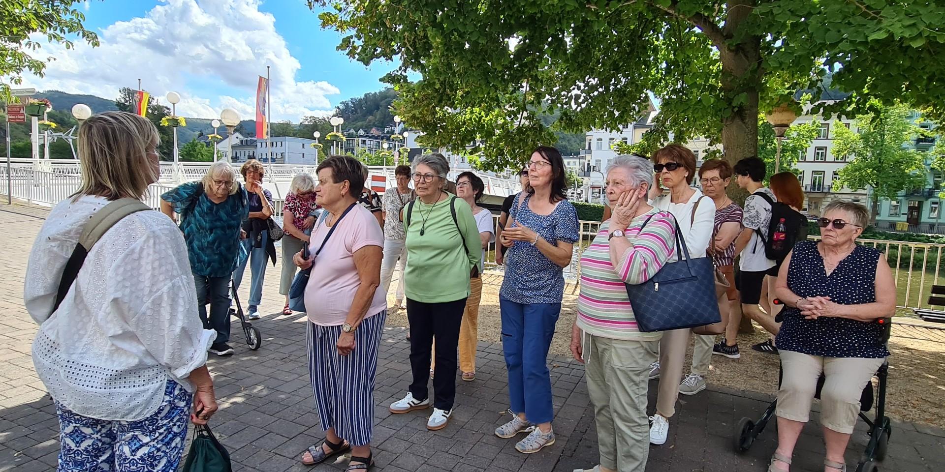 Man sieht Frauen am Ufer eines Flusses stehen, darüber blauer Himmel mit weißen Wolken
