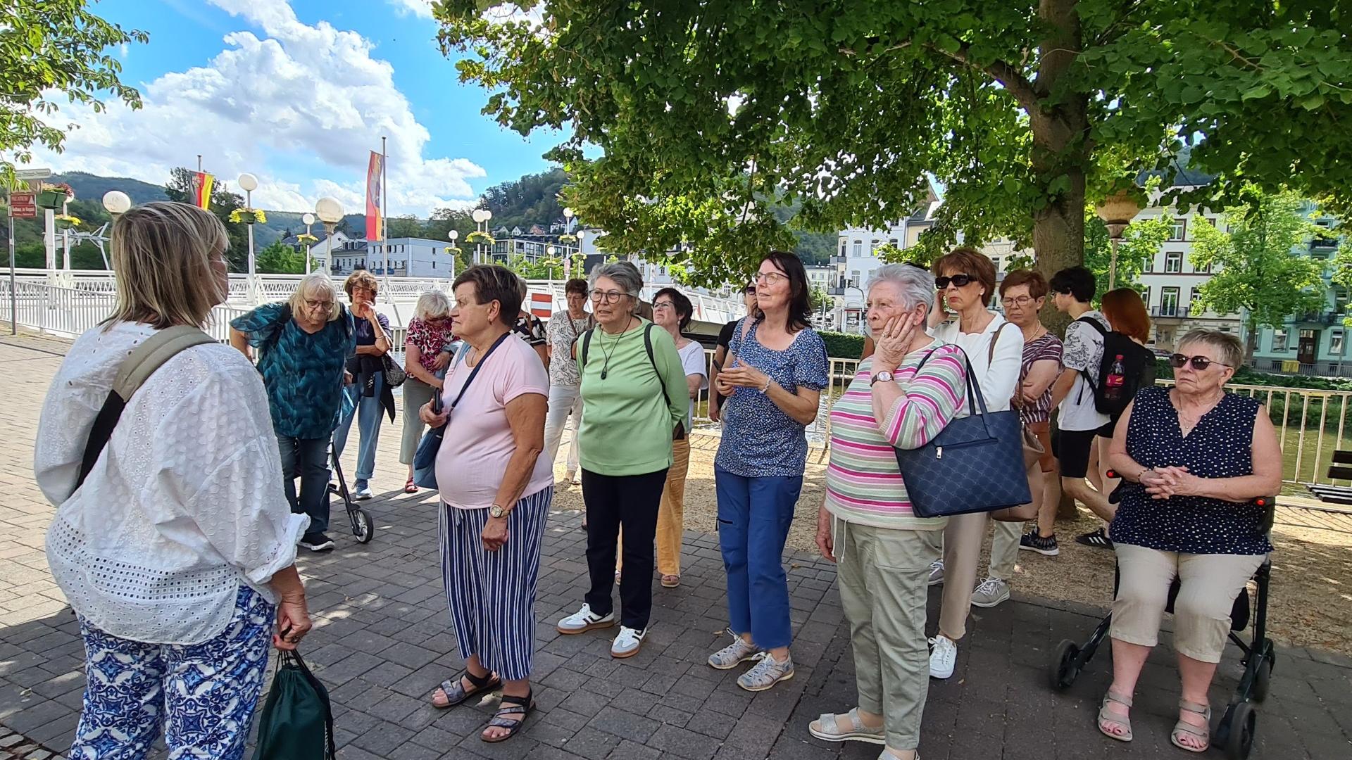 Man sieht Frauen am Ufer eines Flusses stehen, darüber blauer Himmel mit weißen Wolken