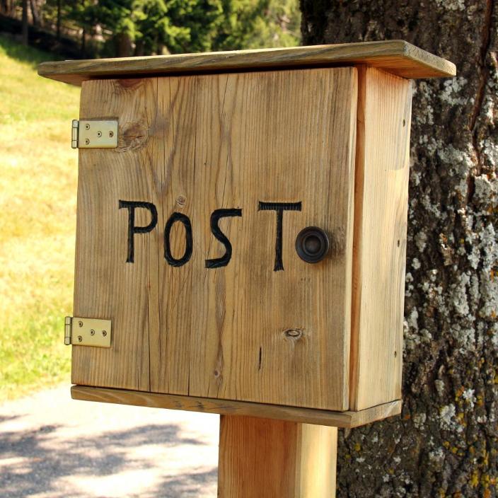 Man sieht an einem Baum einen Holzbriefkasten mit der Aufschrift 'Post'