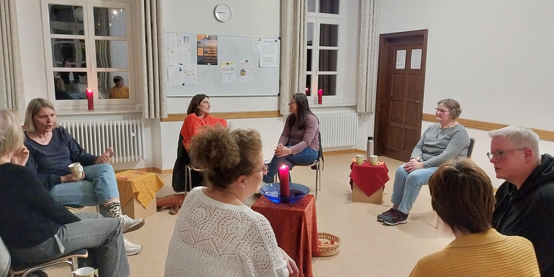 Man sieht eine Gruppe von Menschen in einem Kreis sitzend, sich unterhalten