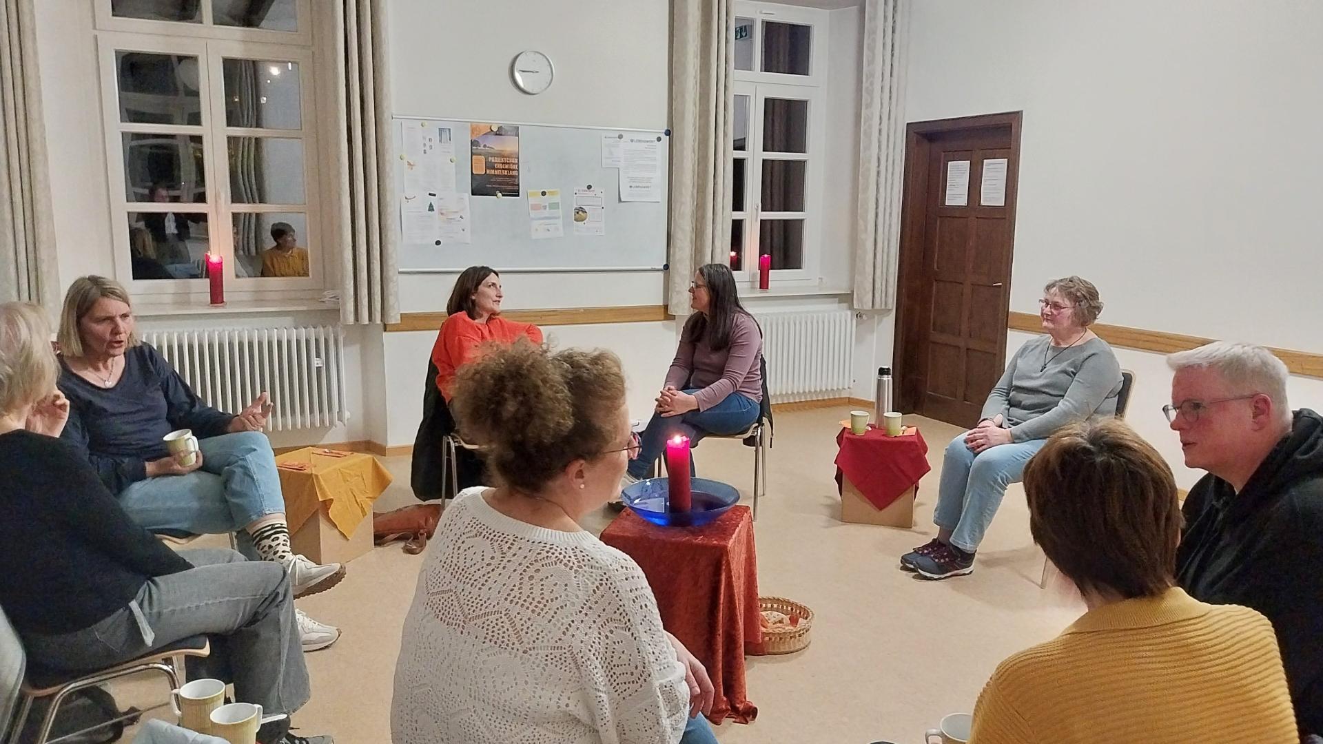 Man sieht eine Gruppe von Menschen in einem Kreis sitzend, sich unterhalten